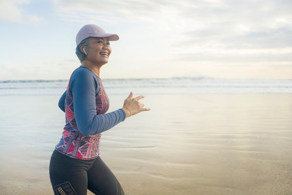 A photo of an older woman going on her morning jog along the beach.