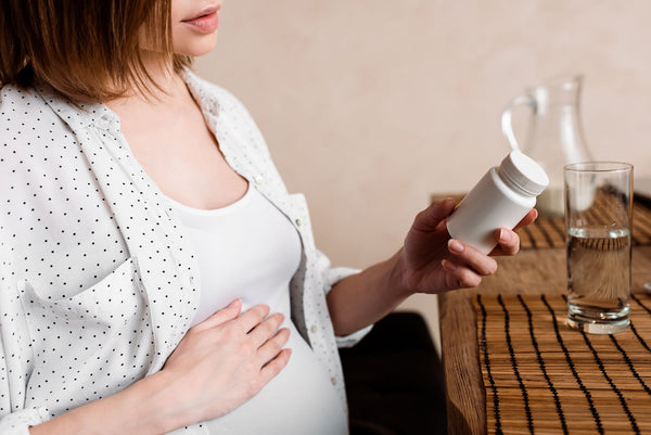 "Expectant mother holding acetaminophen bottle with concerned expression, illustrating difficult decisions about medication use during pregnancy amid new research